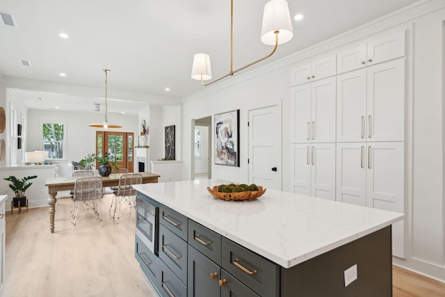 4620 Ohear Ave, North Charleston, SC 29405 - kitchen featuring stainless steel microwave, light wood-style floors, decorative light fixtures, white cabinetry, and a kitchen island