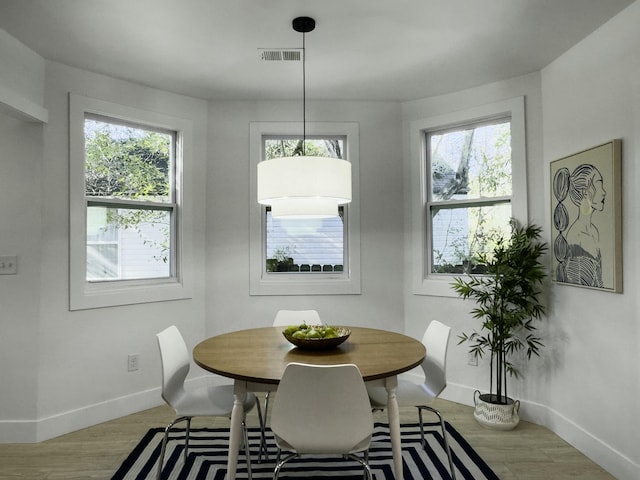 dining space with baseboards, visible vents, and wood finished floors