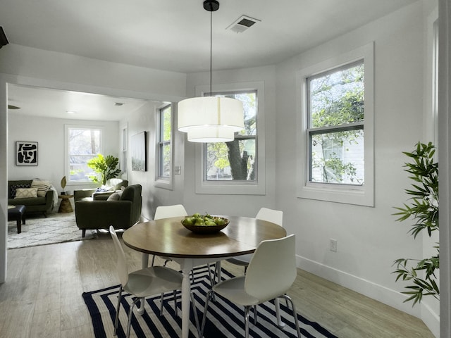 dining area featuring light wood-style flooring, visible vents, and baseboards