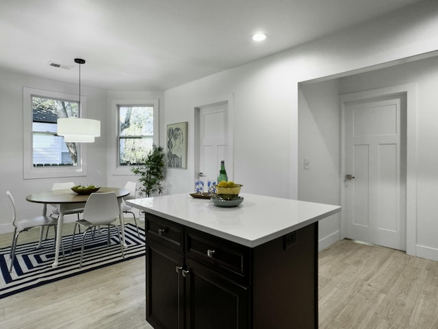 kitchen featuring dark cabinets, visible vents, light countertops, light wood-type flooring, and a center island