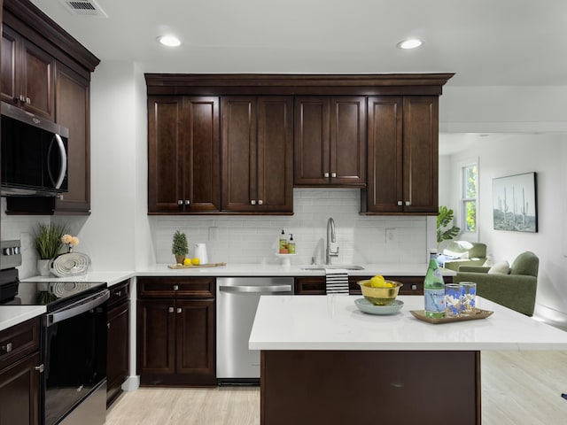 kitchen featuring dark brown cabinets, appliances with stainless steel finishes, light countertops, and a sink