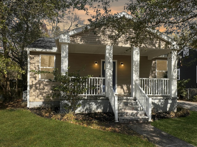 bungalow featuring a porch and a lawn