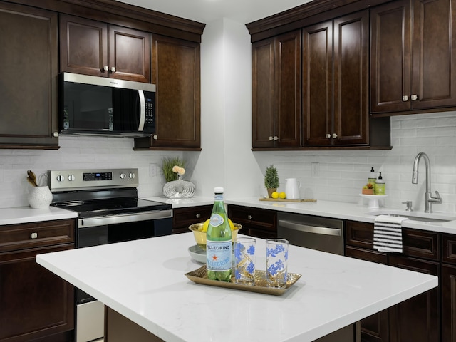 kitchen featuring stainless steel appliances, decorative backsplash, a sink, dark brown cabinetry, and a kitchen island