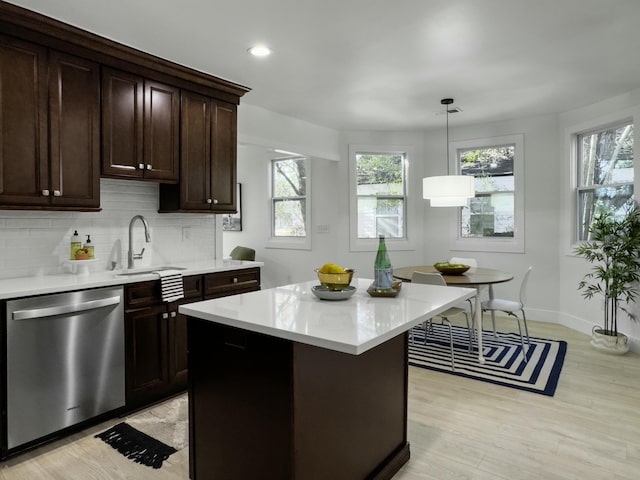 kitchen featuring light countertops, backsplash, stainless steel dishwasher, a sink, and dark brown cabinets