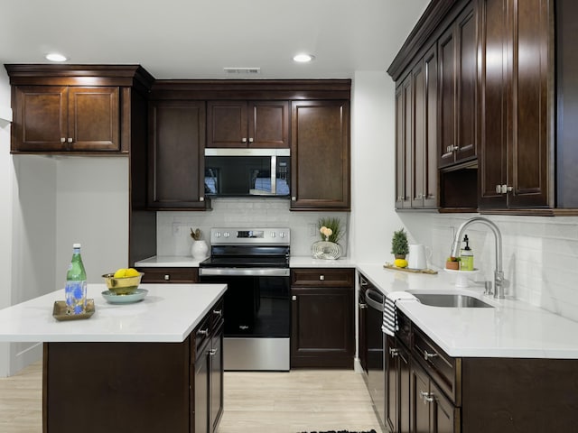 kitchen featuring dark brown cabinetry, appliances with stainless steel finishes, light countertops, and a sink