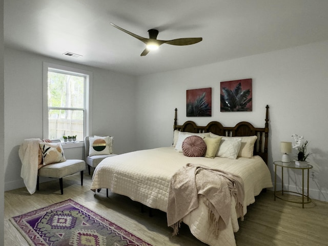 bedroom featuring visible vents, ceiling fan, baseboards, and wood finished floors