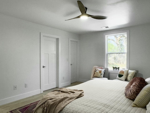 bedroom featuring baseboards, visible vents, ceiling fan, and wood finished floors