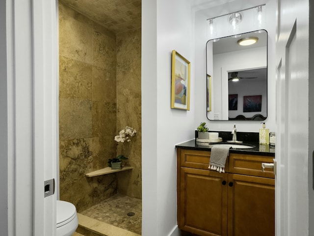 bathroom featuring toilet, a tile shower, and vanity