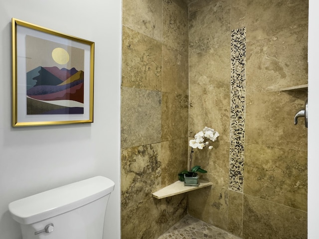 bathroom featuring a tile shower and toilet