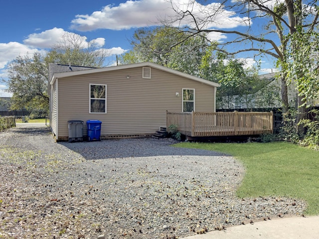 view of property exterior with a yard, gravel driveway, and a wooden deck