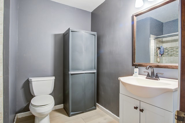 bathroom featuring vanity, toilet, and a shower with door