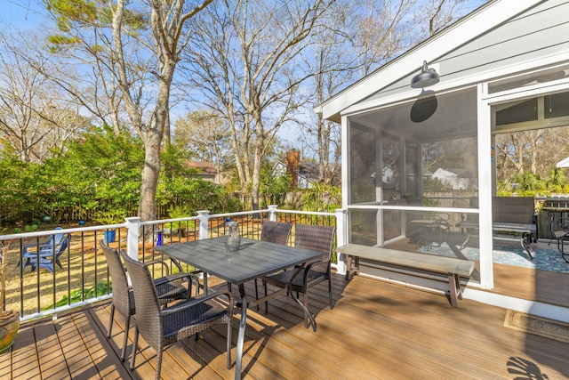 wooden deck featuring a sunroom and outdoor dining area