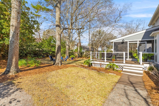 view of yard with a deck, fence, and a sunroom