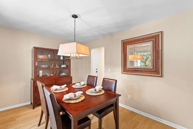 dining space with light wood-type flooring and baseboards