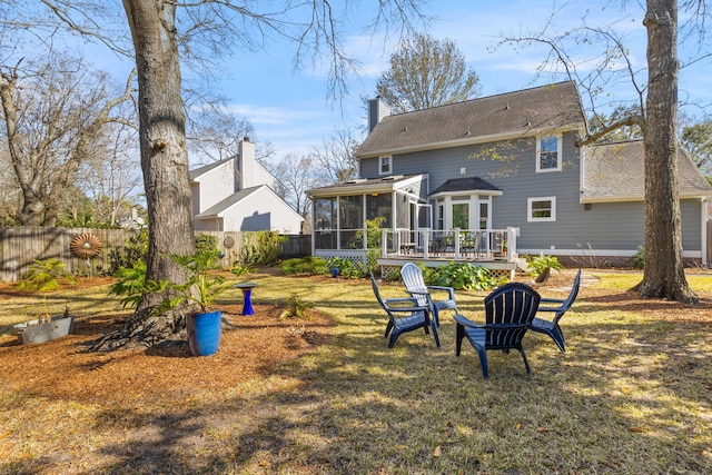 rear view of house with a sunroom, a chimney, fence, and a yard