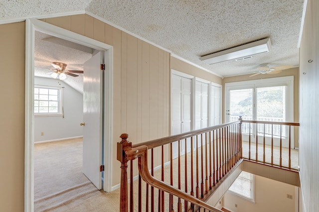 corridor with vaulted ceiling, a textured ceiling, and light colored carpet