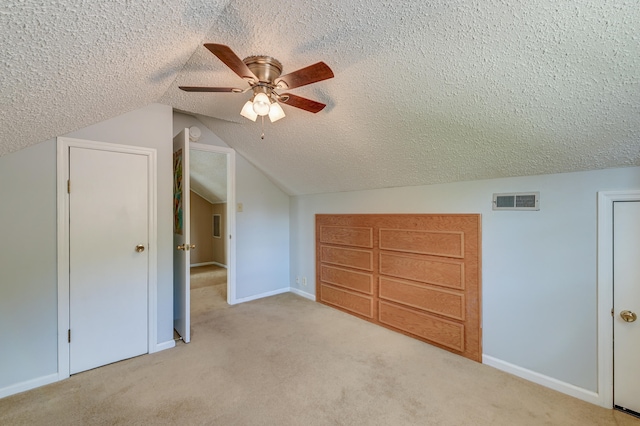 bonus room featuring ceiling fan, a textured ceiling, lofted ceiling, and light colored carpet