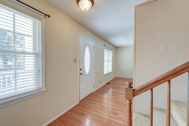 entrance foyer featuring light hardwood / wood-style floors, a textured ceiling, and a healthy amount of sunlight