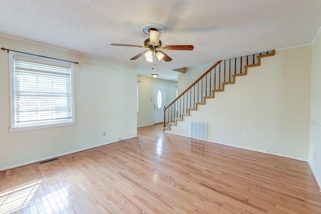 interior space featuring ornamental molding, a textured ceiling, light wood-type flooring, and ceiling fan