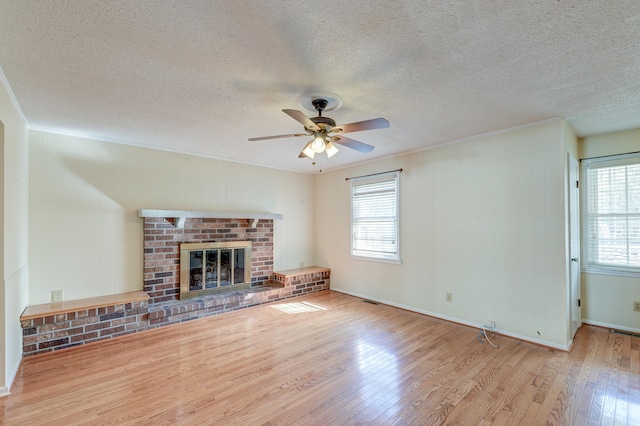 unfurnished living room with a wealth of natural light, light hardwood / wood-style flooring, and a textured ceiling