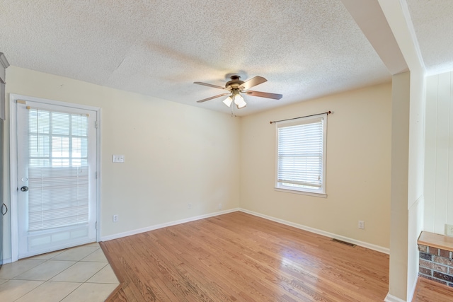 unfurnished room with ceiling fan, a textured ceiling, and light wood-type flooring