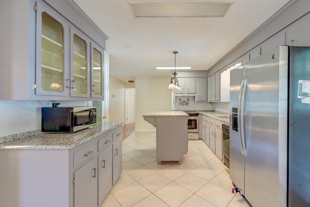 kitchen featuring a kitchen island, hanging light fixtures, backsplash, appliances with stainless steel finishes, and light stone counters