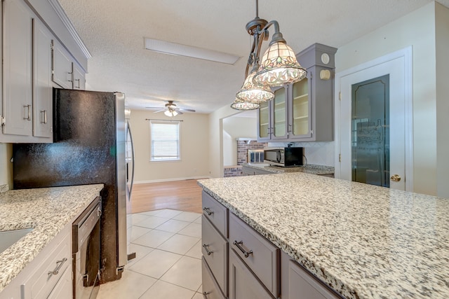 kitchen with hanging light fixtures, light tile patterned floors, appliances with stainless steel finishes, a textured ceiling, and ceiling fan