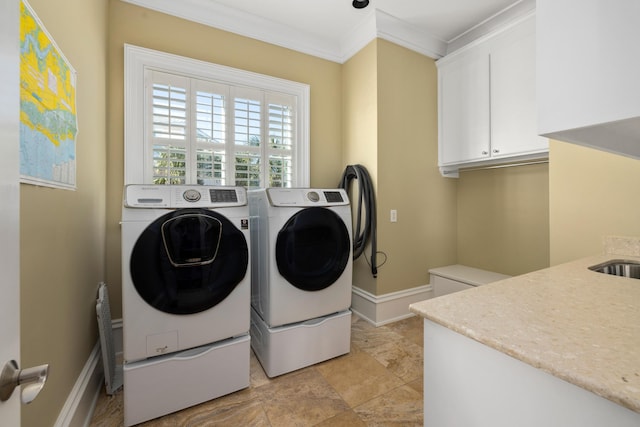 washroom with ornamental molding, cabinet space, washer and clothes dryer, and baseboards