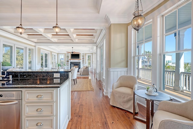 kitchen featuring decorative light fixtures, light wood-style floors, open floor plan, dark stone countertops, and a lit fireplace