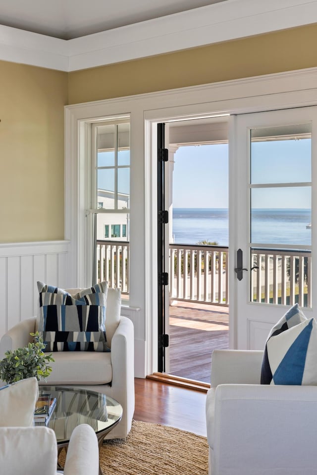 doorway to outside with wainscoting, a water view, and wood finished floors