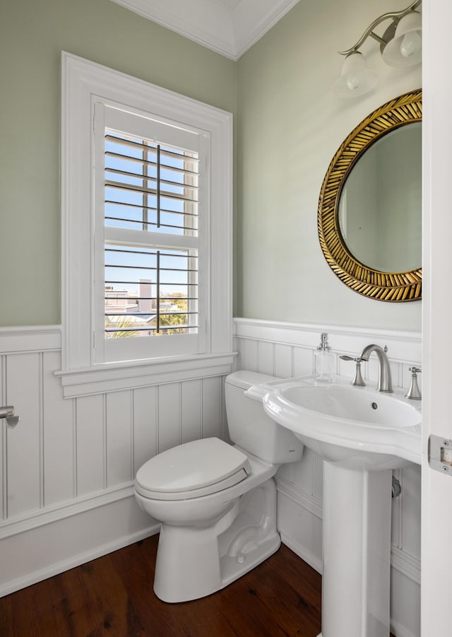 bathroom featuring a wainscoted wall, wood finished floors, toilet, and crown molding