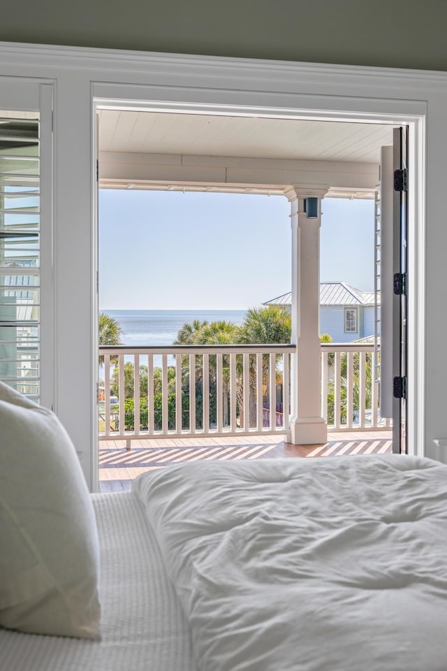 bedroom with a water view, decorative columns, and access to exterior