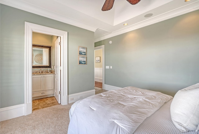 bedroom with crown molding, baseboards, ensuite bath, and light colored carpet