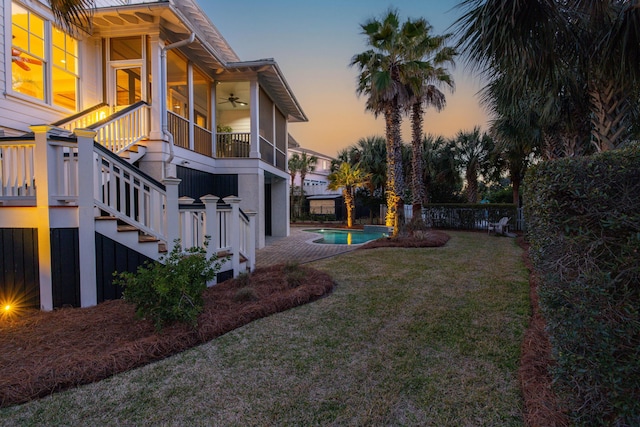 yard at dusk featuring a fenced in pool, a ceiling fan, a patio, stairway, and fence