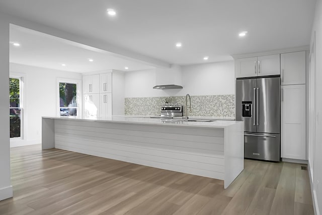 kitchen featuring white cabinetry, light hardwood / wood-style floors, sink, appliances with stainless steel finishes, and wall chimney range hood