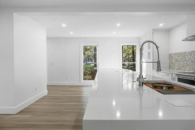 kitchen with white cabinetry, backsplash, and light hardwood / wood-style flooring