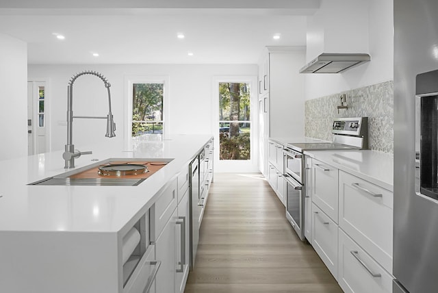 kitchen with sink, white cabinetry, range with two ovens, and light hardwood / wood-style floors