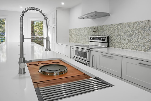 kitchen featuring white cabinets, plenty of natural light, tasteful backsplash, and double oven range