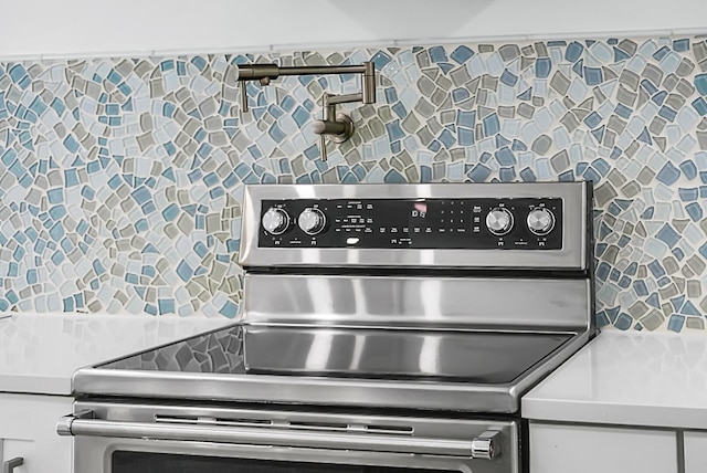 kitchen featuring electric stove and white cabinets