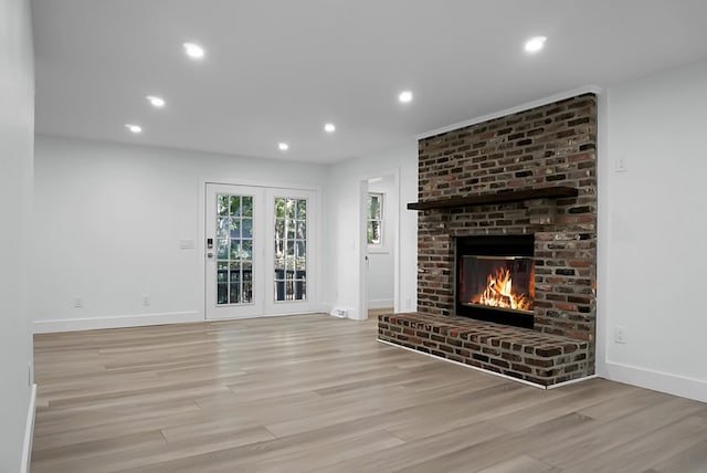 unfurnished living room featuring a brick fireplace and light hardwood / wood-style floors