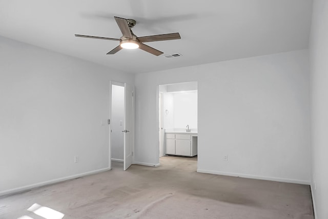 unfurnished bedroom featuring light carpet, ceiling fan, ensuite bathroom, and sink