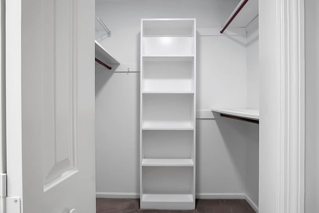 walk in closet featuring dark colored carpet