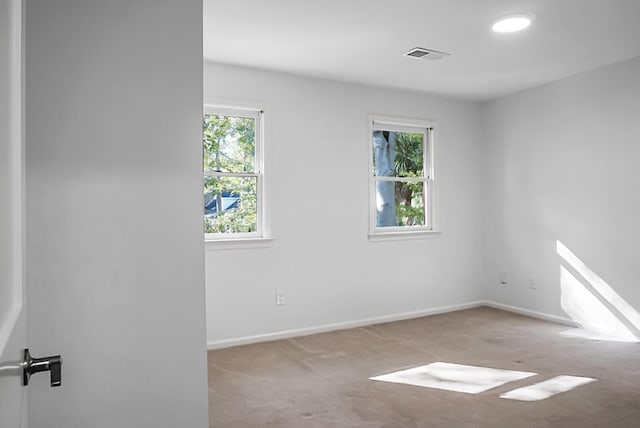 unfurnished room with light colored carpet and a wealth of natural light