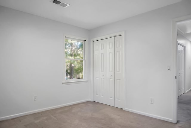 unfurnished bedroom with a closet and light colored carpet