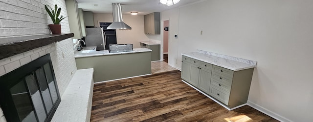 kitchen with dark wood-type flooring, sink, gray cabinetry, kitchen peninsula, and a fireplace