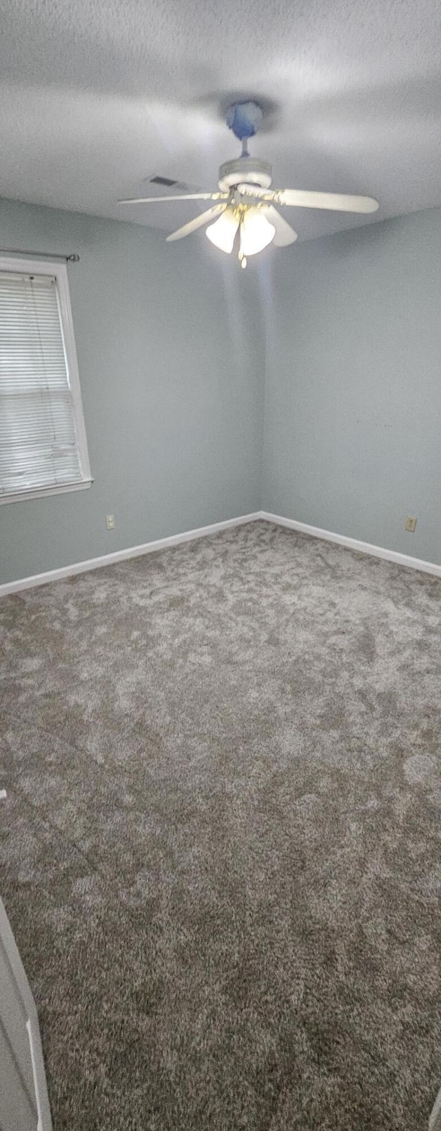 unfurnished room with ceiling fan, carpet, and a textured ceiling