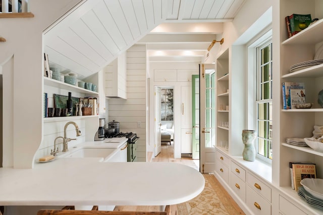 interior space with vaulted ceiling, stainless steel gas range oven, a sink, and light wood-style flooring