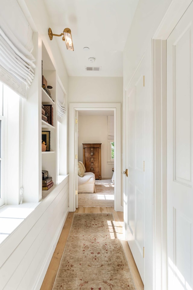 hallway featuring visible vents and light wood-style floors