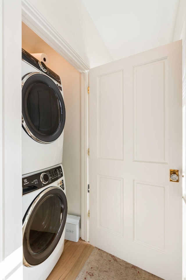 washroom featuring laundry area, stacked washing maching and dryer, and wood finished floors