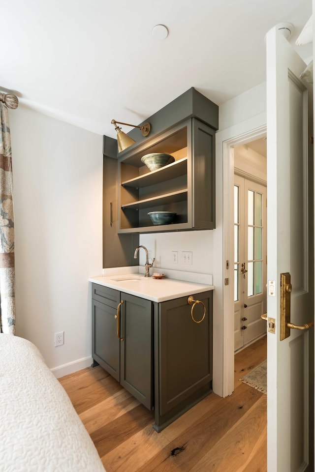 bar featuring light wood-style floors, a sink, and baseboards